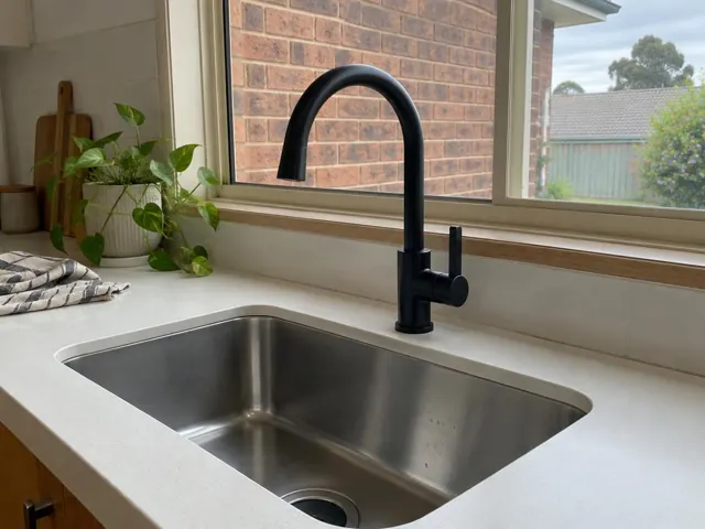 Black kitchen mixer tap beside a stainless steel sink under a window in a modern kitchen in Valentine
